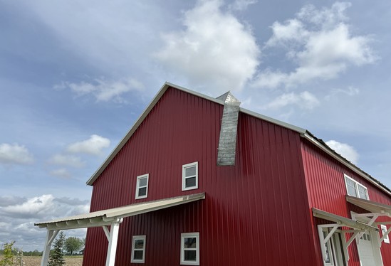 Gable end of a restored red barn against a blue sky