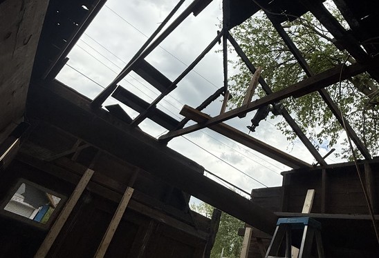 Open garage rafters with sky visible before the new roof deck went on