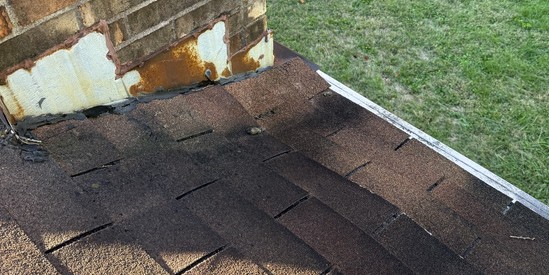 Rusted chimney flashing and deteriorated shingles before replacement