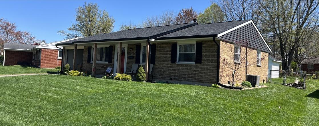 The same brick ranch with a finished dark architectural shingle roof