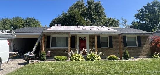 Brick ranch home with its roof stripped to underlayment before shingles