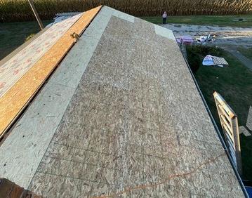 New roof decking installed over a ranch home beside a cornfield