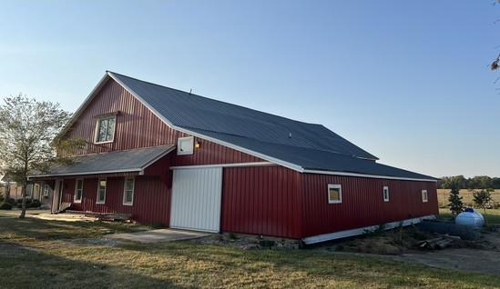 Red barn with a new dark standing-seam metal roof after restoration