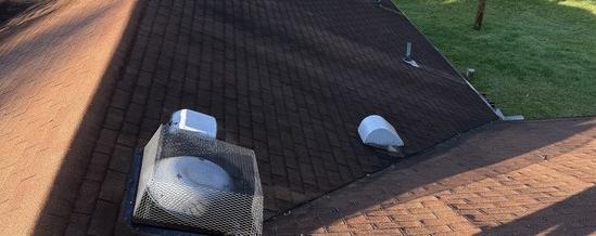 Old faded shingles and worn roof vents before replacement