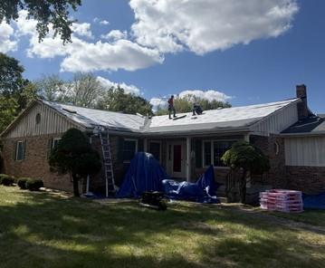 Crew on a ranch roof during tear-off with tarps protecting the landscaping