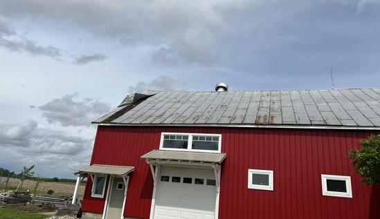 Red barn with a rusted, worn metal roof before replacement