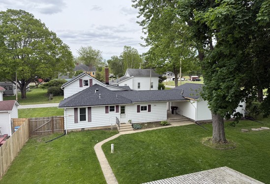 Aerial view of a finished shingle roof replacement on a white two-story home